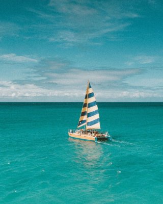 Levendige zeilboot op helder turquoise zeewater onder een heldere lucht, vastleggend een perfect zomeravontuur